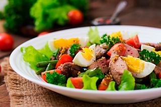 A vibrant salad with chicken, eggs, tomatoes, and greens served at Bistrot La Bohéme on MSC Seaside | MSC Cruises