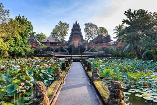 A serene pathway leads through lush greenery towards a stunning temple in Benoa, Bali | MSC Cruises