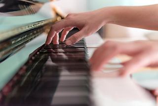 A close-up of hands playing the piano, creating beautiful music and enhancing the onboard entertainment experience | MSC Cruises