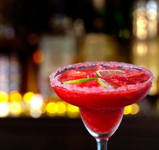 A vibrant margarita cocktail with lime slices served in a glass, set against a lively bar backdrop | MSC Cruises