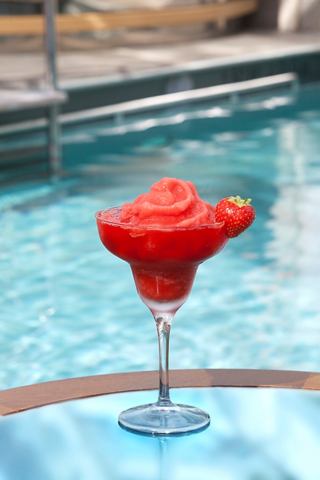 A refreshing strawberry daiquiri in a glass sits by a shimmering pool, inviting relaxation and enjoyment | MSC Cruises