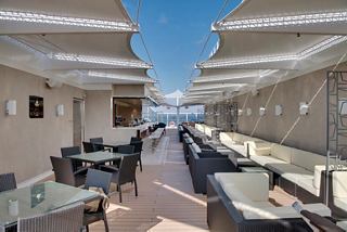 A spacious lounge area with comfortable seating and a view of the sea, inviting relaxation aboard MSC Seaside | MSC Cruises