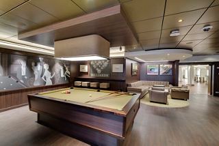 Une salle de billard élégante avec une table de billard et un coin salon confortable pour la détente et le divertissement | MSC Cruises