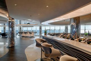 A stylish bar lounge with panoramic sea views, featuring a sleek counter and comfortable seating | MSC Cruises
