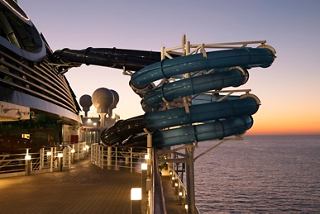 Panoramablick auf das Deck der MSC Seaside mit Wasserrutsche und Sonnenuntergang über dem Meer | MSC Cruises