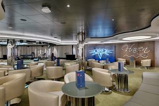 A welcoming lounge area with comfortable seating, a stage, and a screen for entertainment | MSC Cruises