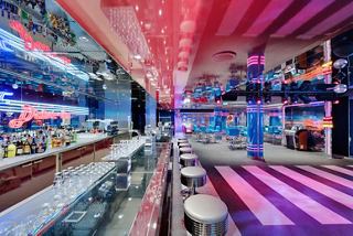 A vibrant disco bar area on the MSC Seaside featuring a dance floor, bar counter, and colourful lighting | MSC Cruises