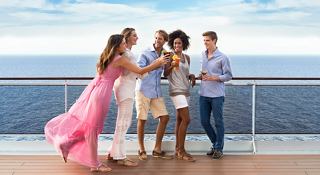 A group of friends enjoying drinks and toasting together on the deck of MSC Preziosa with a stunning sea backdrop | MSC Croisières
