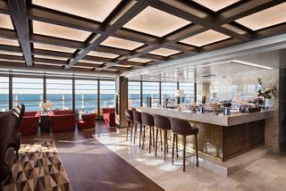 Elegant seating area with a bar counter and panoramic sea views, inviting relaxation and enjoyment | MSC Cruises