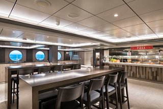 A spacious and inviting restaurant area with tables and portholes, perfect for dining experiences at sea | MSC Cruises