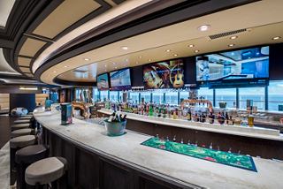 A vibrant sports bar with a sleek counter and large screens, inviting guests to enjoy refreshments while overlooking the sea | MSC Cruises
