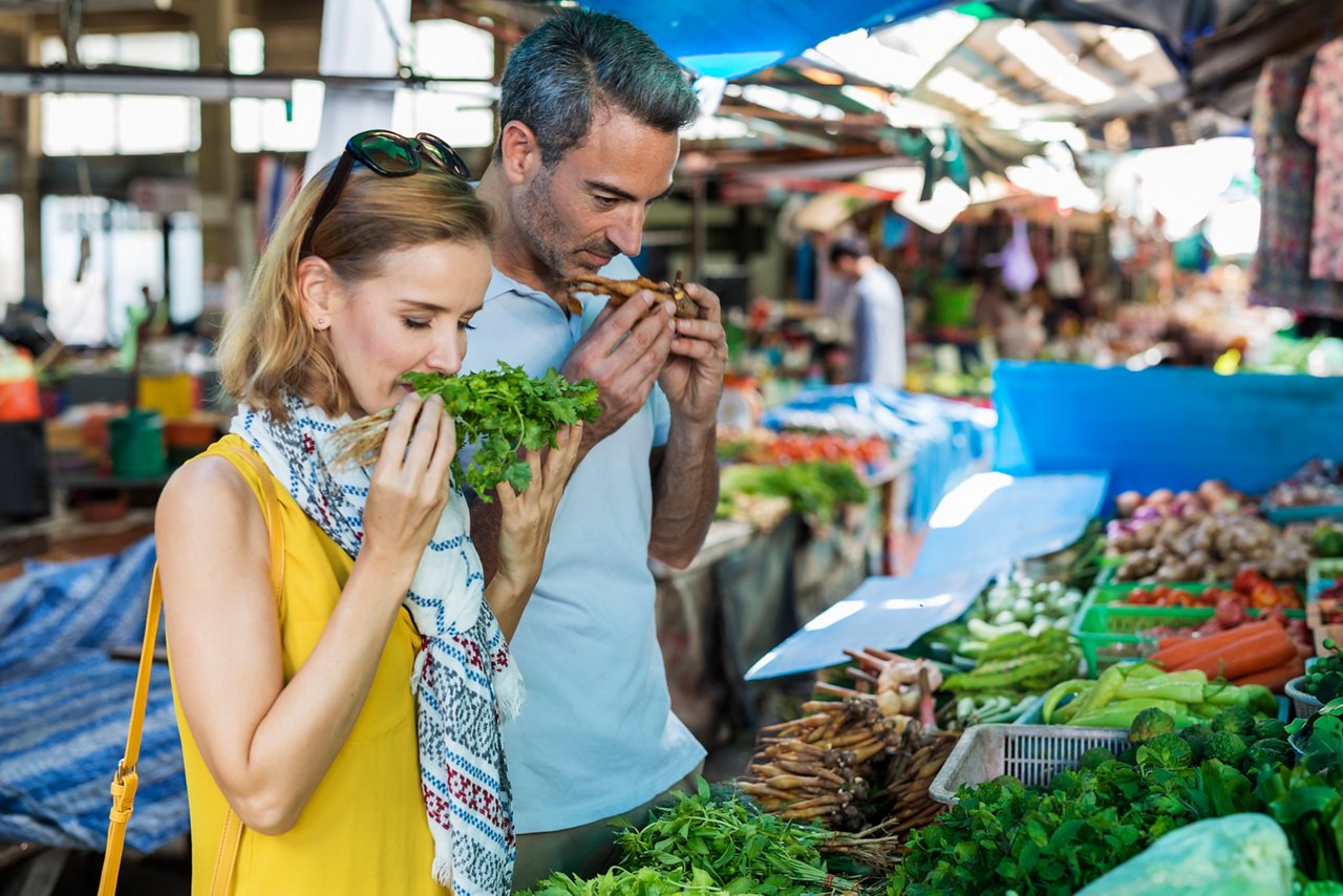 A couple explores a vibrant market, selecting fresh vegetables to enhance their culinary experience | MSC Cruises