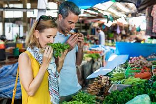 A couple explores a vibrant market, selecting fresh vegetables to enhance their culinary experience | MSC Cruises