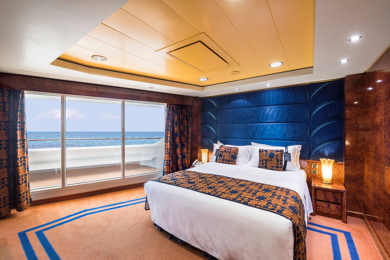 Bright and spacious executive suite featuring a double bed and sea views through large windows | MSC Cruises