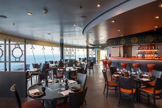 Un restaurante espacioso con asientos elegantes y vistas panorámicas al mar | MSC Cruceros