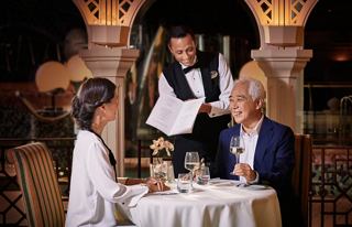 A couple enjoys a fine dining experience at L'Olivo Restaurant with attentive service from a waiter | MSC Cruises
