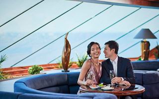 A couple enjoys a moment in the Top Sail Lounge with a view of the sea | MSC Cruises