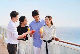 Friends enjoying cocktails on a cruise deck, overlooking the sea and sharing a joyful moment together | MSC Cruises