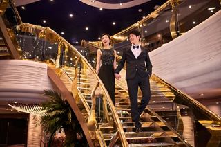 Un couple élégant descend gracieusement le grand escalier à bord du MSC Splendida | MSC Croisières