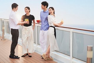Un couple déguste des boissons non alcoolisées sur le pont du MSC Splendida tout en échangeant avec un membre du personnel sur fond de mer | MSC Cruises