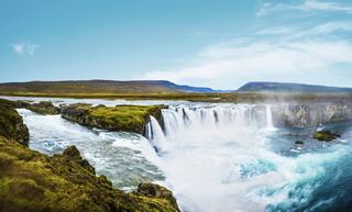 Majestic Godafoss Waterfall surrounded by lush landscape under a clear blue sky in Iceland | MSC Cruises