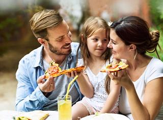 A family enjoys pizza together, sharing joyful moments over soft drinks in a vibrant restaurant setting | MSC Cruises