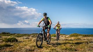 A couple enjoys a scenic mountain bike tour with a stunning sea view in the background | MSC Cruises