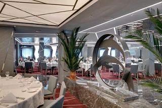 Elegant dining area in the Silver Dolphin restaurant, featuring tables, chairs and scenic portholes | MSC Cruises