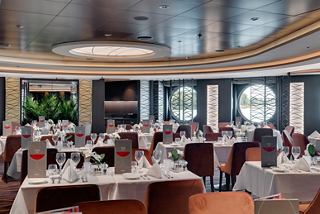 Spacious dining area with elegant tables and large windows offering a warm atmosphere | MSC Cruises