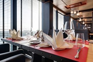 Una mesa de comedor bellamente dispuesta con cubiertos elegantes y servilletas, con vistas a impresionantes vistas oceánicas | MSC Cruceros