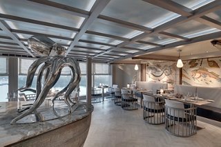 A stylish restaurant featuring a contemporary sculpture and large windows with ocean views | MSC Cruises