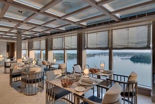 A stylish restaurant with elegant tables by large windows overlooking the sea on MSC Seaview | MSC Cruises