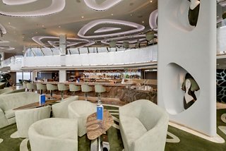 A stylish interior of the MSC Yacht Club's Top Sail Lounge featuring comfortable seating and a welcoming bar area | MSC Cruises