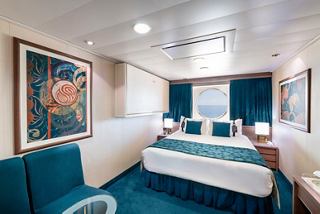 A spacious ocean view cabin featuring a double bed, Pullman bed, porthole, sofa, and table with inspiring decor | MSC Cruises