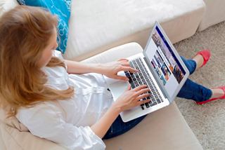 A woman books her next adventure online while relaxing on a sofa | MSC Cruises
