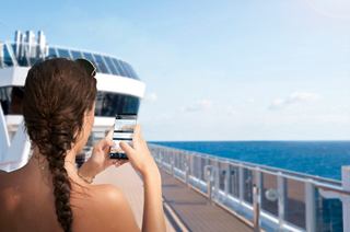 A woman captures a moment on her smartphone while enjoying the sea view from the deck of MSC Divina | MSC Cruises