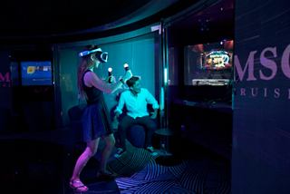 Teens enjoy interactive gaming in a vibrant entertainment area aboard MSC Meraviglia | MSC Cruises