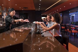 Una pareja disfruta de una deliciosa experiencia gastronómica en Kaito Sushi Bar, interactuando con el chef sobre cocina fresca | MSC Cruceros