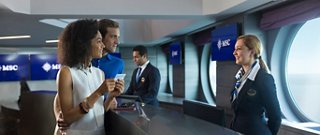 Una joven pareja conversa con la tripulación del crucero, disfrutando de un ambiente cálido y acogedor | MSC Cruceros