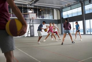 Des adolescents profitent d'un match de basket-ball animé dans une lumineuse zone sportive intérieure à bord du MSC Meraviglia | MSC Cruises