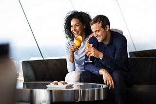 A couple enjoys drinks and snacks together in a stylish lounge with a sea view on the MSC Meraviglia | MSC Cruises