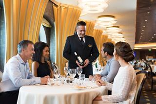 A sommelier serves wine to a group of friends enjoying a meal in a restaurant aboard MSC Meraviglia | MSC Cruises