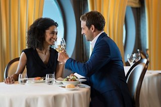 A couple enjoying a romantic dinner with wine, celebrating together in a restaurant aboard MSC Meraviglia | MSC Cruises