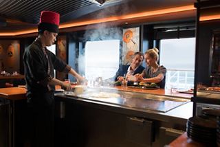 Un chef prepara una comida en el restaurante Teppanyaki mientras los invitados disfrutan de su experiencia en el bar | MSC Cruceros