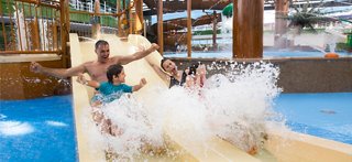 Families enjoying a thrilling waterslide experience at the Aquapark onboard a cruise ship | MSC Cruises