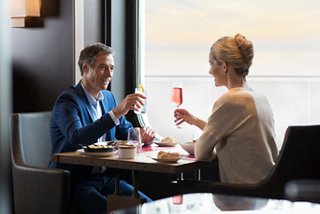 A couple enjoys a toast with wine while dining together in a restaurant with a sea view | MSC Cruises