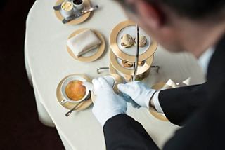 A crew member elegantly arranges pastries and tea in the luxurious MSC Yacht Club | MSC Cruises