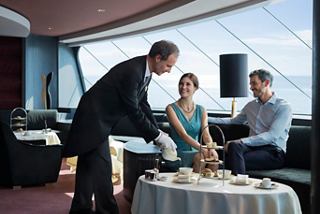 A couple enjoys refreshments served by a butler in the elegant Top Sail Lounge with panoramic sea views | MSC Cruises