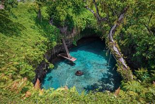 Aerial view of the To Sua Ocean Trench surrounded by lush greenery and a ladder leading down to the pool of water | MSC Cruises