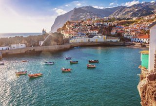 A serene view of Camara de Lobos harbour in Madeira, featuring boats on calm waters and a picturesque coastline | MSC Cruises